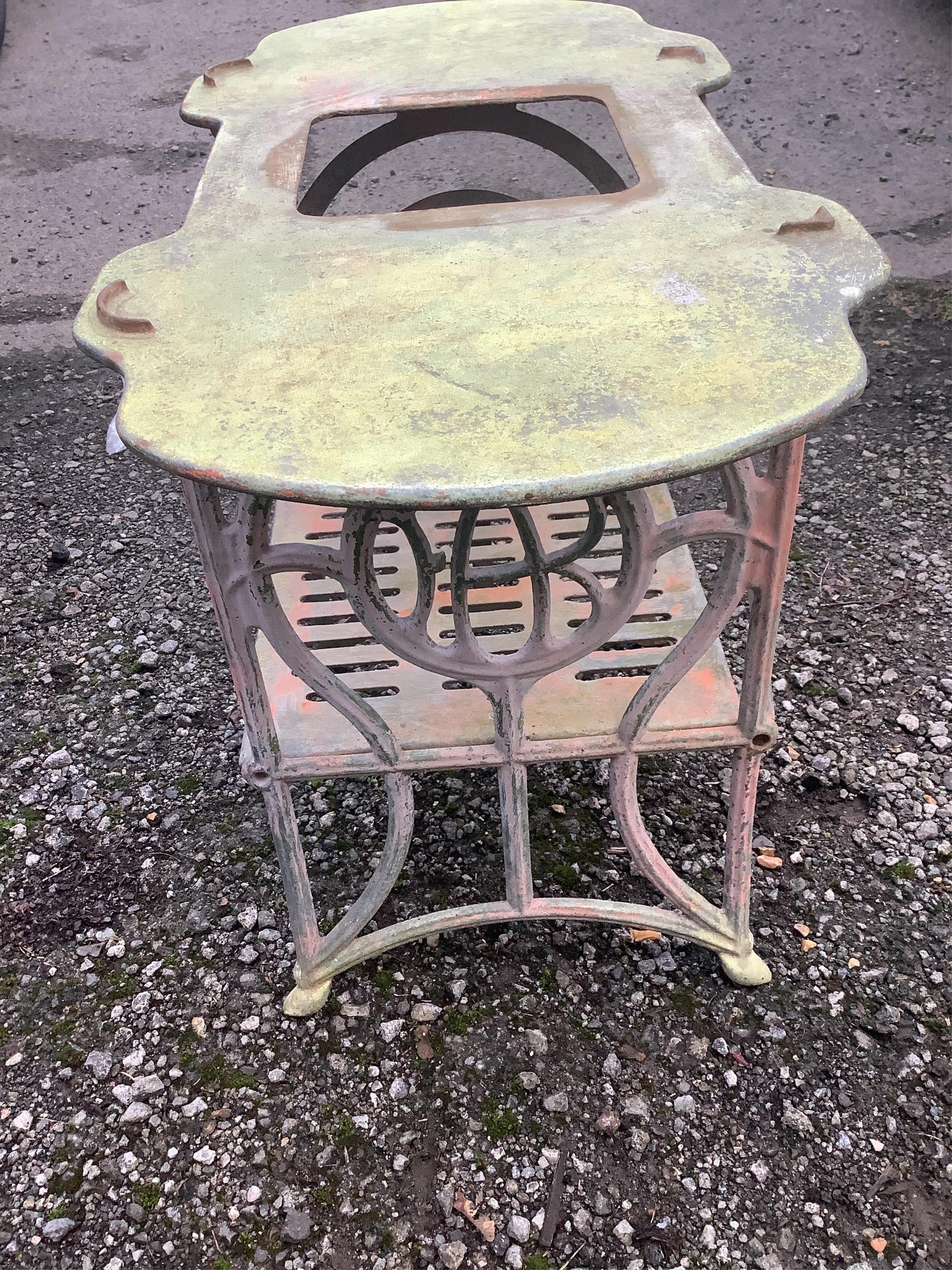 A small white painted cast metal two tier table, with a shaped top, width 78cm, height 59cm. Condition - fair